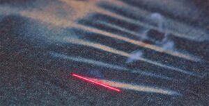 Laser finishing technology on raw denim jeans replacing traditional sandblasting.