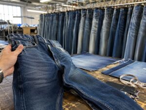 approved denim sample compared against bulk production jeans inside a denim development workspace