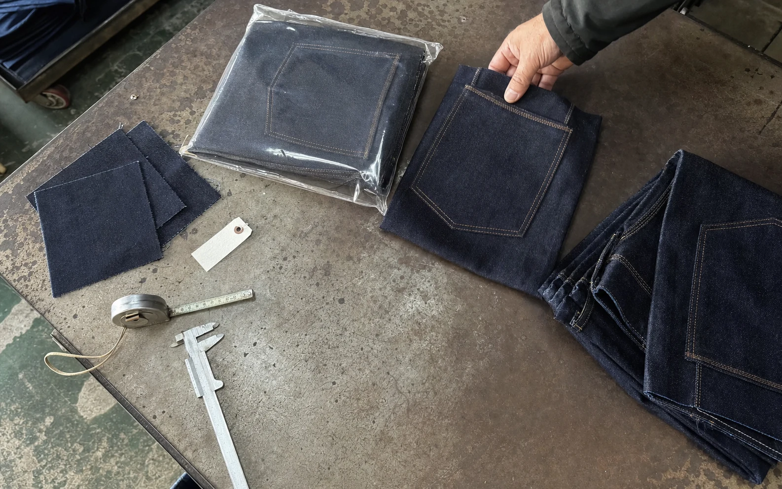 Approved denim sample, fabric swatches and measurement tools prepared for reorder baseline verification